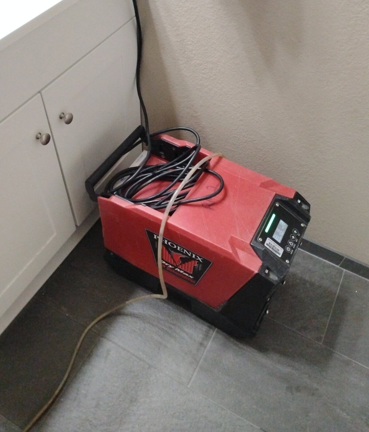 Red dehumidifier for water damage restoration in Cave Creek, AZ, on tile floor.