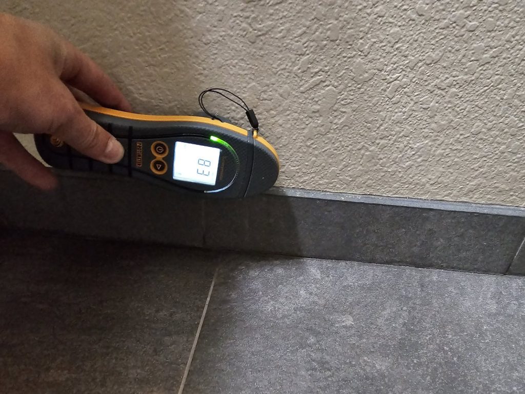 Hand holding a moisture meter reading checking for water damage restoration in Cave Creek, AZ.